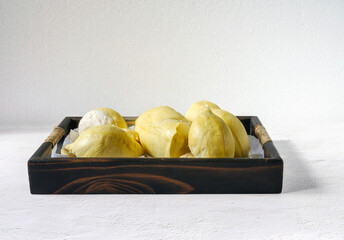 A yellow durian that has been peeled off to reveal the tasty yellow flesh of the durian. Durian fruit on wooden basket