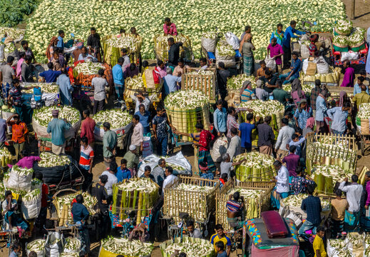 Bogura, Bangladesh - 27 November 2019: Aerial view of a bustling marketplace where vibrant crowds gather amidst heaps of fresh produce, creating a tapestry of colors and textures..