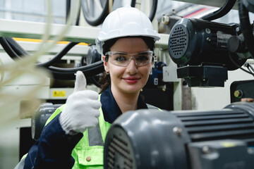 Female technician inside modern factory gives approval with thumbs up amid complex machinery...