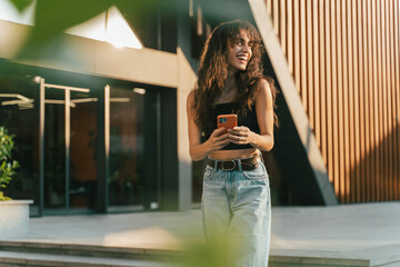 Attractive young latin woman using smartphone in the city