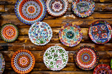 Colorful hand painted ceramic plates on rustic wooden wall display
