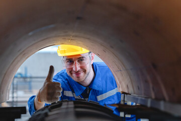 Team of engineers, male and female, in reflective uniforms and helmets, collaborate in inspecting complex cardboard machine components inside paper packaging factory.