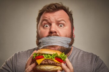 Man Craving Burger with Mouth Taped Shut – Diet Struggle Concept