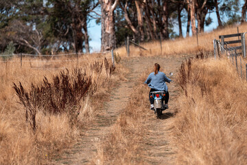 working in agriculture. girl riding a motorbike on a farm in outback Australia. Ranch worker...