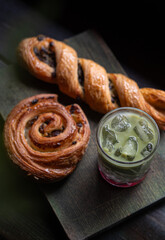 Refreshing iced strawberry matcha latte served with assorted pastries on a rustic wooden table in a cozy coffee shop. Aesthetic cafe atmosphere, perfect for a relaxing break or brunch, captured in nat