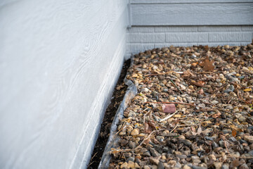 Pulling the rock and weed barrier away from a wall foundation for painting.