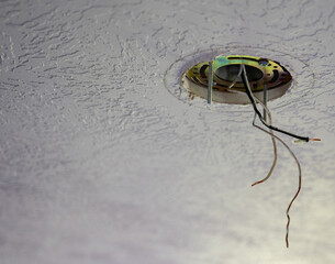 Ceiling fixture installation process showing exposed wires in a residence during daylight hours