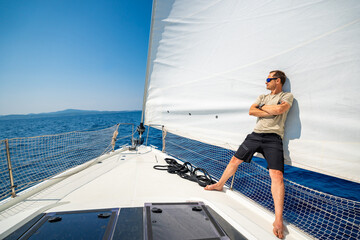 Man leaning on full sails of a sailing yacht in the open sea near Croatia. Masculinity, leadership, yachting and freedom on the water.