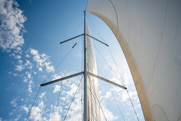 White sails filled with wind, seen from the bow of a sailing yacht near Croatia. Freedom, clean energy, adventure and mindful travel on the open sea.