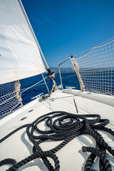 Black rope lying on the bow of a sailing yacht moving under full sails near Croatia. Marine detail, navigation, strength and motion at sea.
