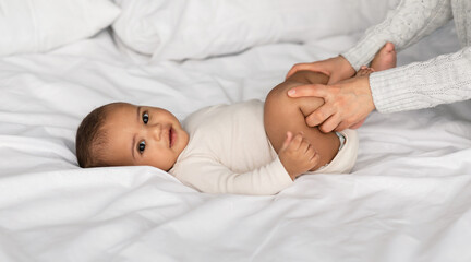 Caring Woman Making Gymnastics To Newborn Baby On Bed At Home, Unrecognizable Lady Helping Infant Kid To Relief Gas, Doing Exercises With Little Kid To Prevent Child Constipation, Moving Legs
