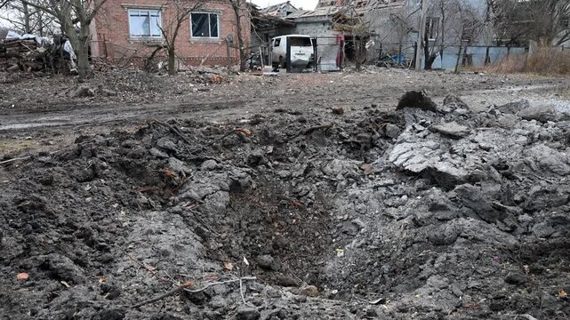 Tilt-up view of a scene of destruction on the outskirts of Kramatorsk in Ukraine's Donbas region. A missile crater and ruined homes are the result of a reported Russian attack on the area.