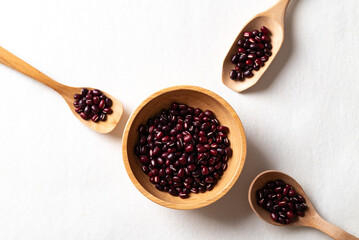 Top view of raw Azuki beans or red mung beans in wooden bowl and spoon on white background, Food ingredient