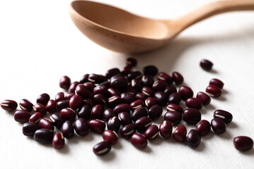 Pile of raw Azuki beans or red mung beans with wooden spoon on white background, Food ingredient