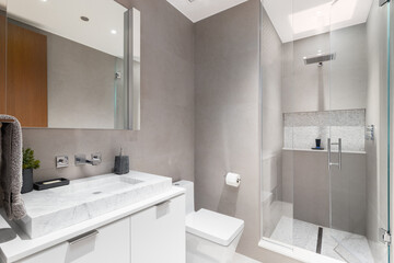 A bathroom with brown tiled walls, a white marble vessel sink on a white cabinet, and a walk-in shower with a square tile shelf and floor.