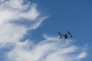 A drone with a camera, a drone flying against the background of a blue sky, an unmanned flying...
