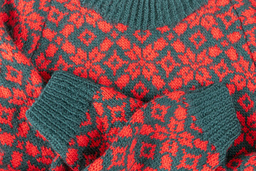 Knitted Christmas sweater in red and green with floral motif and crossed sleeves