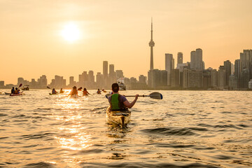 Group of kayakers paddling  into the setting sun and toward the downtown city skyline shot in...
