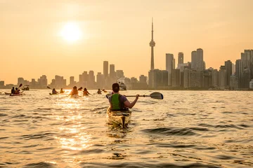 Fototapete Rund Toronto Group of kayakers paddling  into the setting sun and toward the downtown city skyline shot in toronto in summer room for text copy space  © Michael Connor Photo