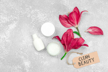 Skincare cosmetics concept with red lily on stone concrete background, flat lay. Natural selfcare