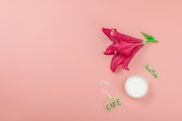 Skincare cosmetics concept with red lily on soft pink background, flat lay. Natural selfcare