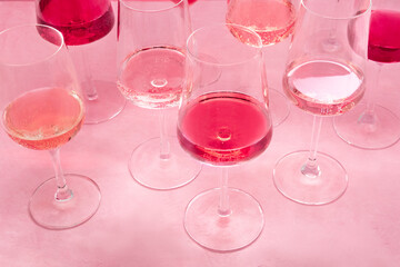 Rose wine tasting, a variety of hues and tints, on a pink background, many wineglasses, vibrant colors