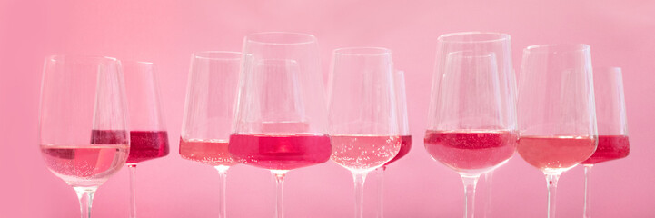 Rose wine tasting panorama, a variety of hues and tints, side view on a pink background, many wineglasses, summer party panoramic banner