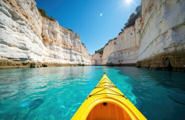 A person kayaking through clear blue water between white chalk cliffs under a bright sunny sky