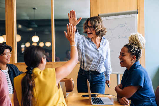 Group high-five during a successful meeting with enthusiastic team members