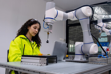 Engineer works with robotic arm in modern lab during day