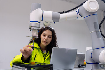 Engineer collaborates with robotic arm to assemble components in a modern manufacturing facility during daytime