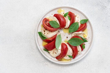 Fresh Caprese Salad with Mozzarella Cheese, Ripe Tomatoes, and Green Basil Leaves on White Background. Healthy Mediterranean Food Concept