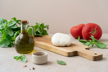 Healthy ingredients for caprese salad: fresh mozzarella, tomatoes, and basil arranged on a wooden board. Rustic kitchen scene, ideal for Mediterranean food concepts
