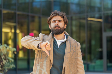 Dislike. Upset Indian Arabian man showing thumb down sign gesture, expressing discontent...