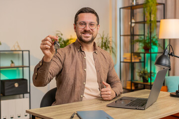 Young businessman real estate agent lifting hand showing the keys of new home house apartment,...