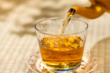 畳の上でやかんから麦茶をグラスに注ぐ和の涼を感じる夏