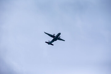 Military Aircraft in Flight, A military transport aircraft flying against a bright blue sky,...