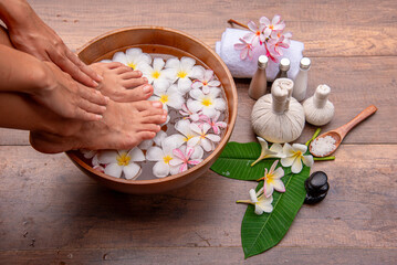 Spa Foot Soak, Relaxing foot spa treatment with herbal compresses, oils, and frangipani flowers in...