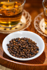 白い器に入った丸粒の大麦と後ろに並ぶ麦茶のグラス