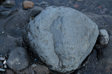 a collection of small and large stones on a beautiful beach on a sunny and cool afternoon