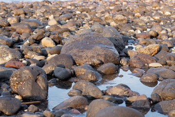 a collection of small and large stones on a beautiful beach on a sunny and cool afternoon