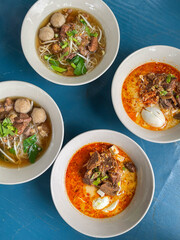 A photography of a bowl of soup with eggs and meat. The closed up of Thai noodles with meat ball. 