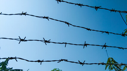 Rusty barbed wire on blue sky background