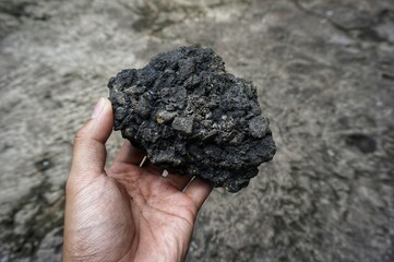 young man holding asphalt stone on damaged road
