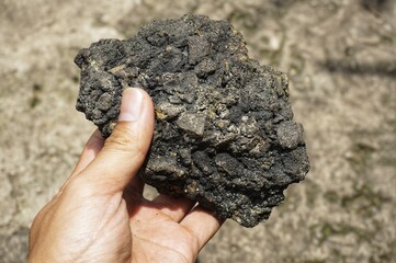 young man holding asphalt stone on damaged road