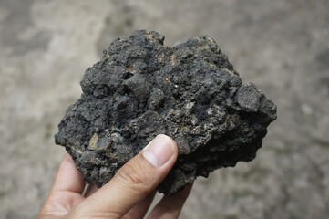 young man holding asphalt stone on damaged road