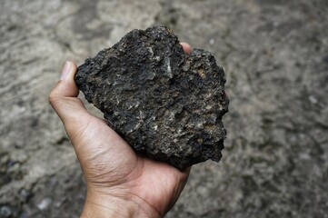 young man holding asphalt stone on damaged road