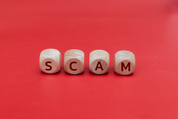 SCAM word spelled on wooden cubes with red background, representing online fraud, scam alert, phishing risk, cybercrime, and financial security threats.