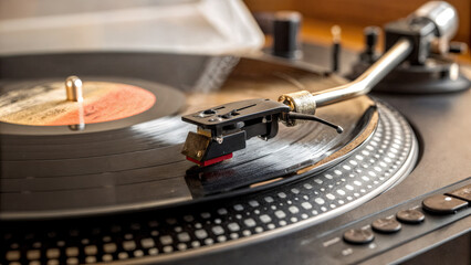 a close-up of a record player with a vinyl record spinning. The stylus of the record player is in contact with the record surface, and the player has several control buttons on the right side.