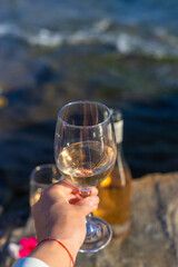 Wine in hands of woman against sea background. Selective focus.